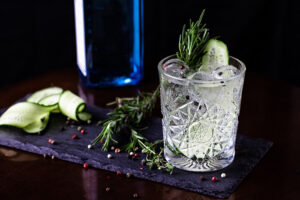 Gin-tonic,Alcoholic,Cocktail.,Cucumber,,Rosemary,,Ice.,On,A,Black,Wooden 0